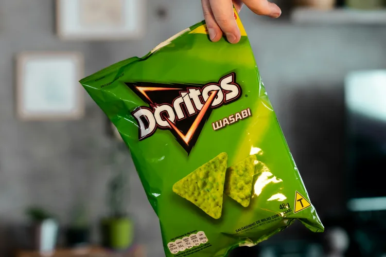 Hand holding sealed Doritos crisp packet to show need for a package leak tester in MAP snacks.
