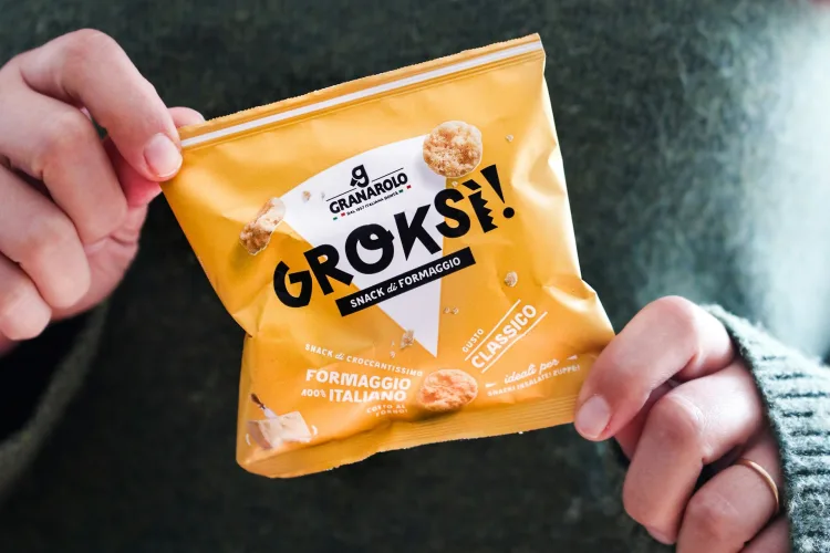 Person holding a sealed flexible snack packaging bag